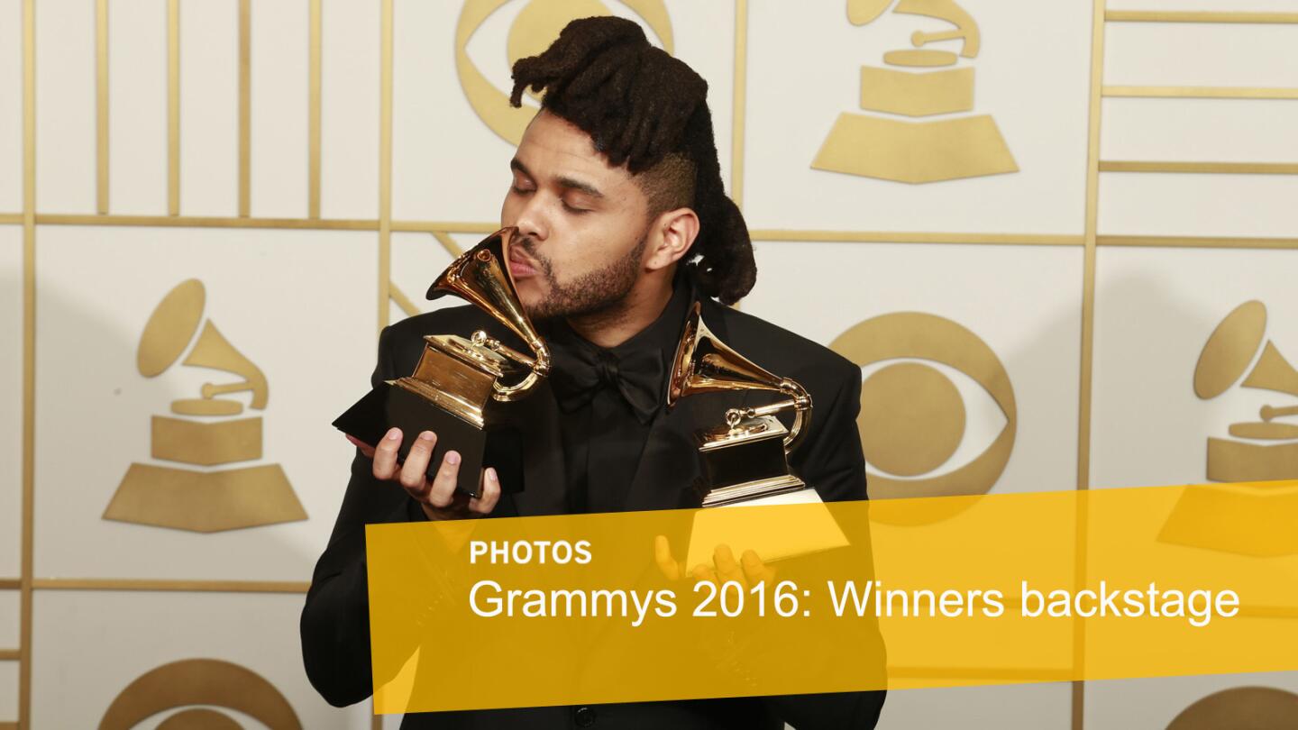 The Weeknd kisses one of his Grammys. He won for R&B performance and urban contemporary album.
