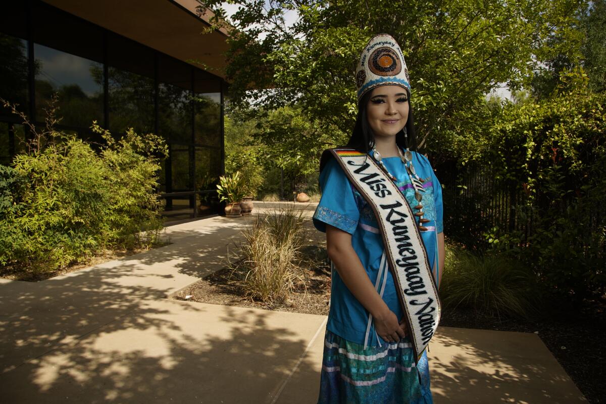 a young woman in traditional, Kumeyaay clothing dons a beaded crown and sash outside