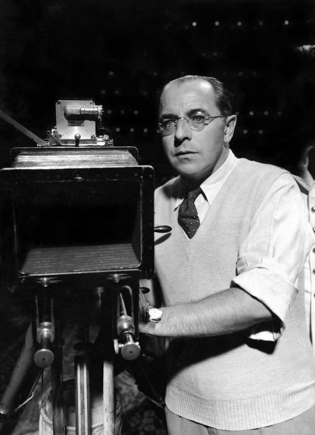 Austrian film director G.W. Pabst wearing a sweater vest and tie and holding a movie camera