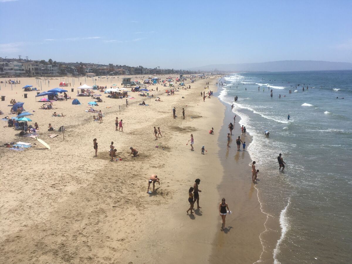 Visitors crowd the beach in Manhattan Beach, Calif., amid the coronavirus pandemic Saturday. Aug. 15, 2020. The heat wave brought dangerously high temperatures, increased wildfire danger and fears of coronavirus spread as people flock to beaches and parks for relief. (AP Photo/John Antczak)
