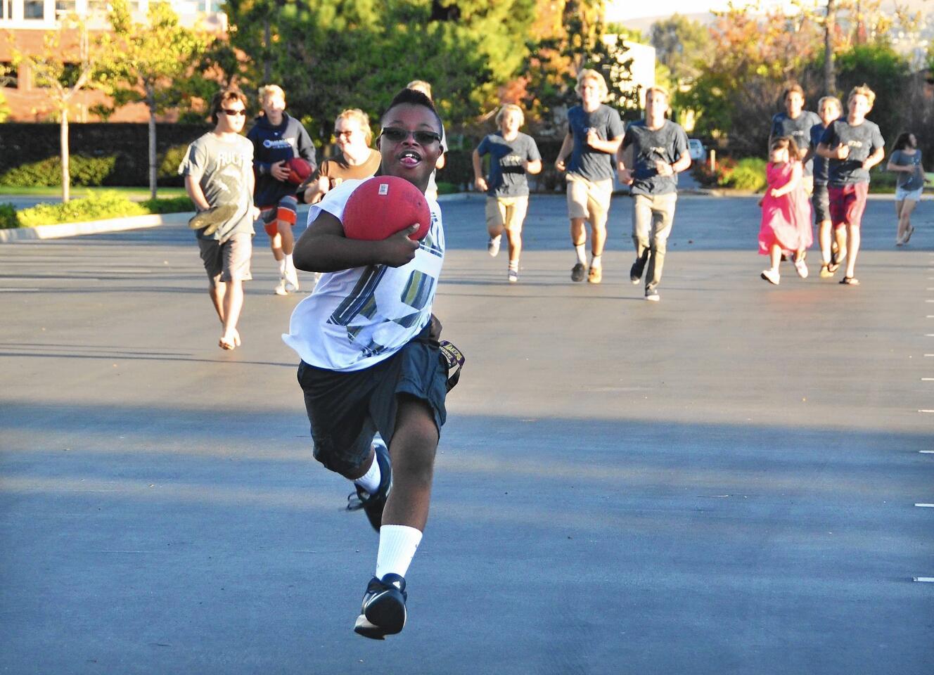 Chris Hobby runs with the ball as the kids and Lions Heart boys take a few laps as part of their outdoor play schedule at the Down Syndrome Foundation Center on Sunday.