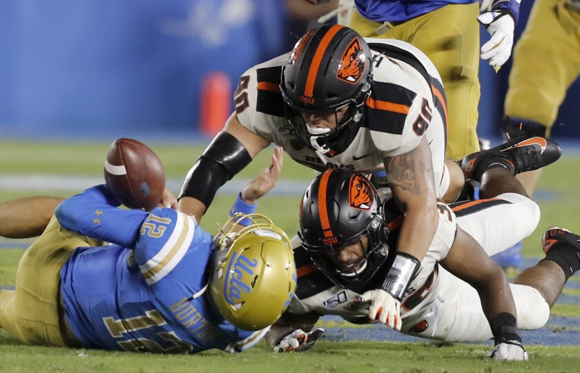 UCLA quarterback Austin Burton is brought down by a pair of Oregon State players in the third quarter Saturday night.