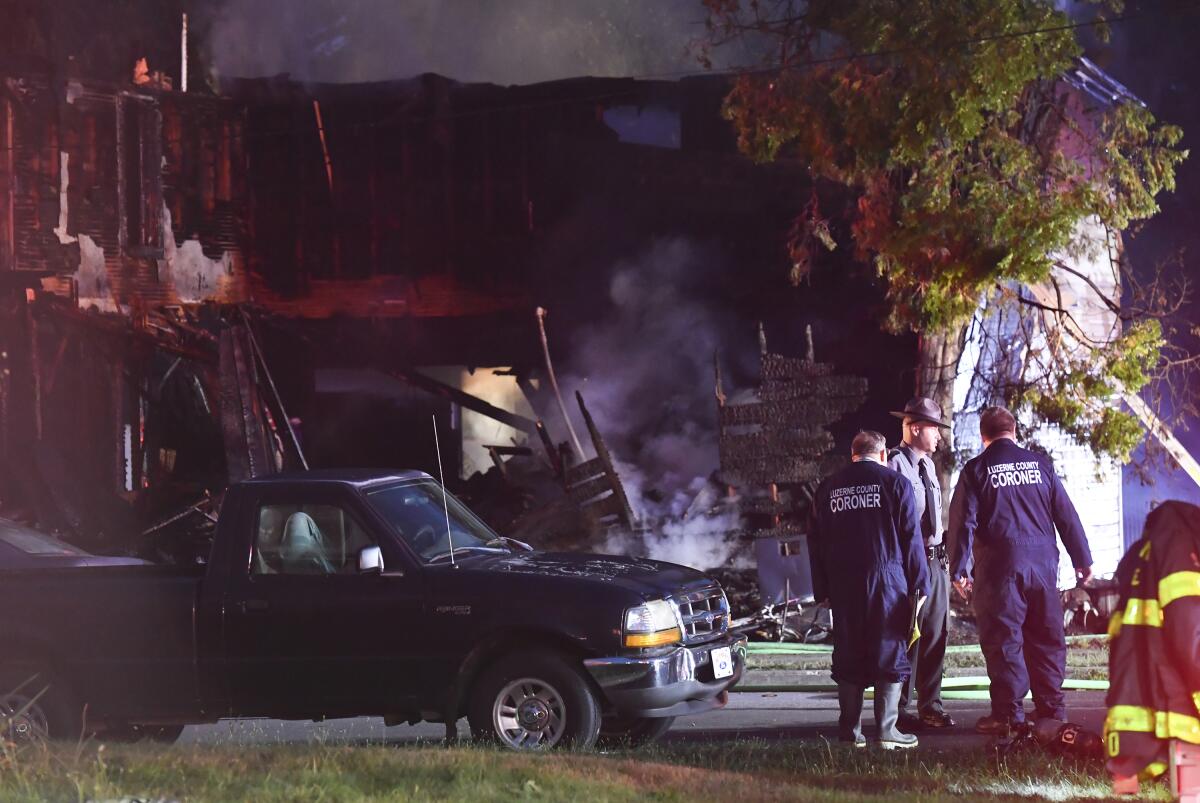 A Pennsylvania State trooper and members of the Luzerne County Coroner Office stand in front of an early morning fatal fire at 733 First Street in Nescopeck, Pa., Friday, Aug. 5, 2022. The fire was reported around 2:30 a.m. The cause of the fire remains under investigation. (Jimmy May/Bloomsburg Press Enterprise via AP)