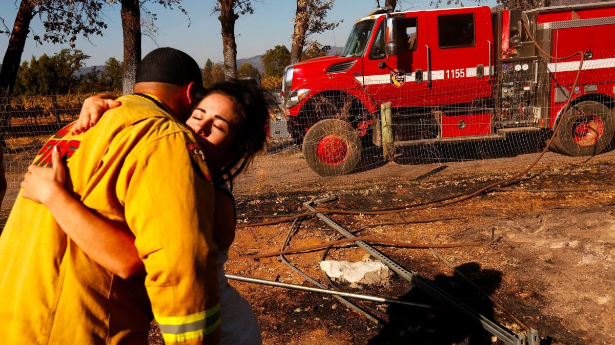 Ashley Oldham, owner of Frost Flower Farms, hugs a firefighter who was putting out hot spots at her marijuana farm in Redwood Valley.
