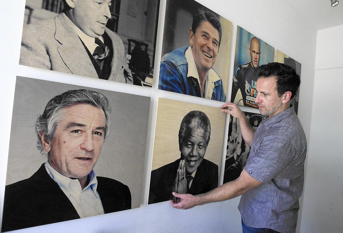 Co-founder Mike Lastrina with an assortment of his favorite personalities printed on wood at the Woodsnap headquarters in Irvine.