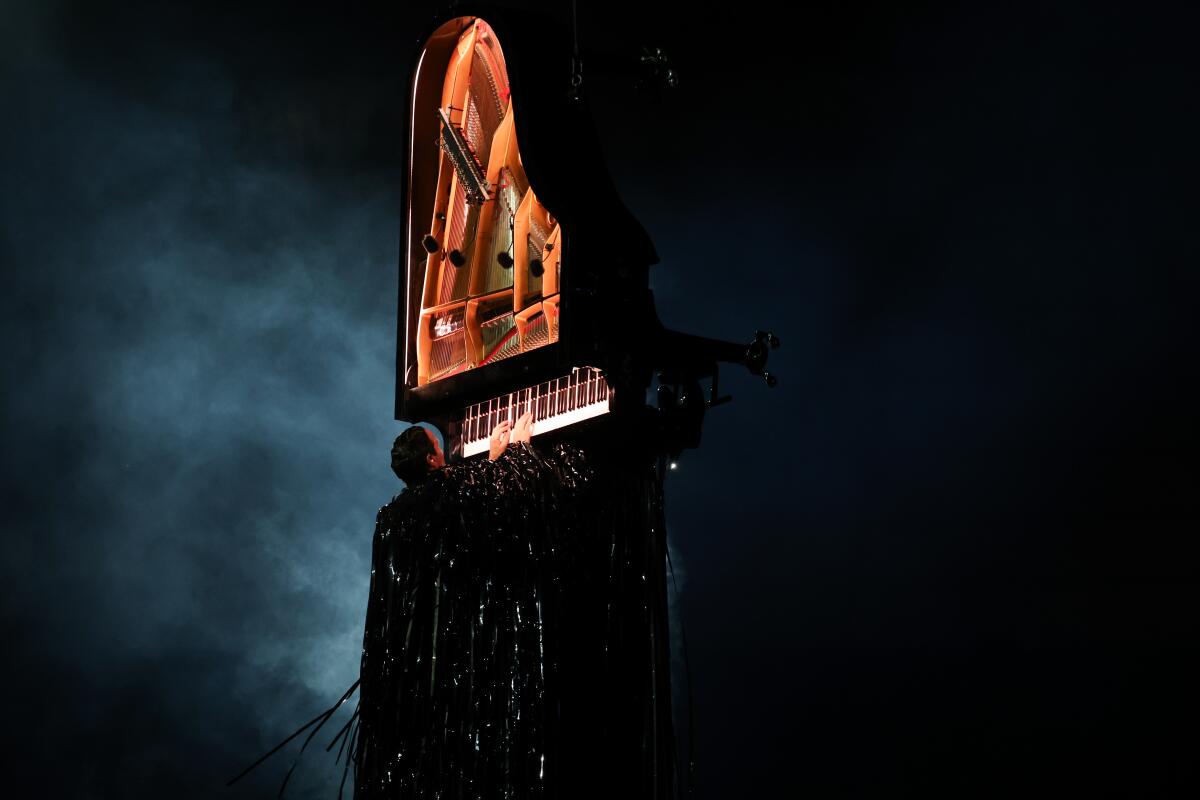 Alain Roche plays a piano hung vertically during the closing ceremony.