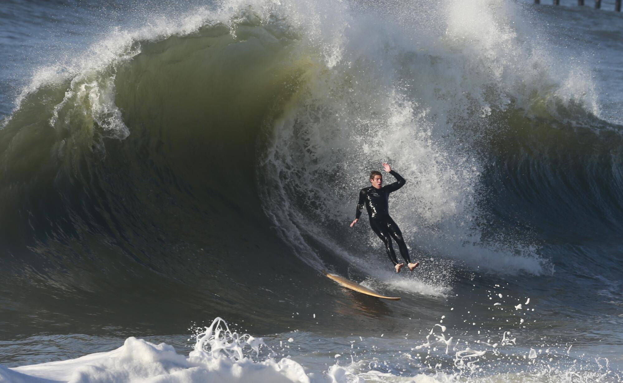 A surfer goes over the falls on a big wave in Seal Beach during stormy weather.