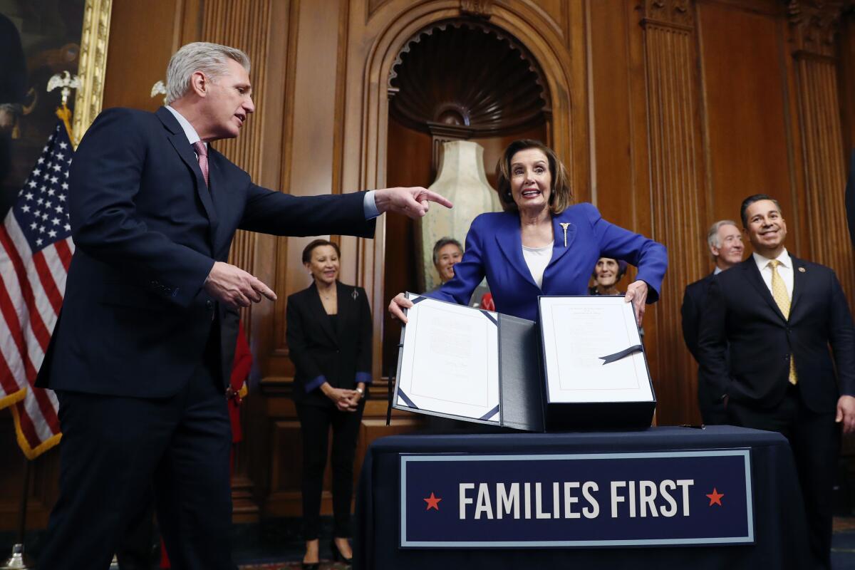 House Speaker Nancy Pelosi, accompanied by House Minority Leader Kevin McCarthy, left, participate in a bill enrollment ceremony for the $2.2 trillion Coronavirus Aid, Relief and Economic Security Act on March 27.