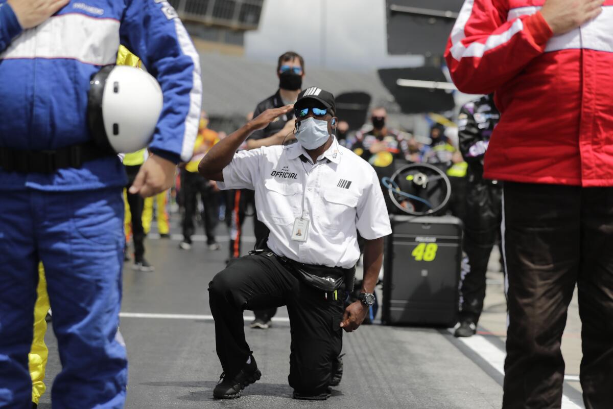 A NASCAR official kneels during the national anthem before a NASCAR Cup Series auto race at Atlanta Motor Speedway.