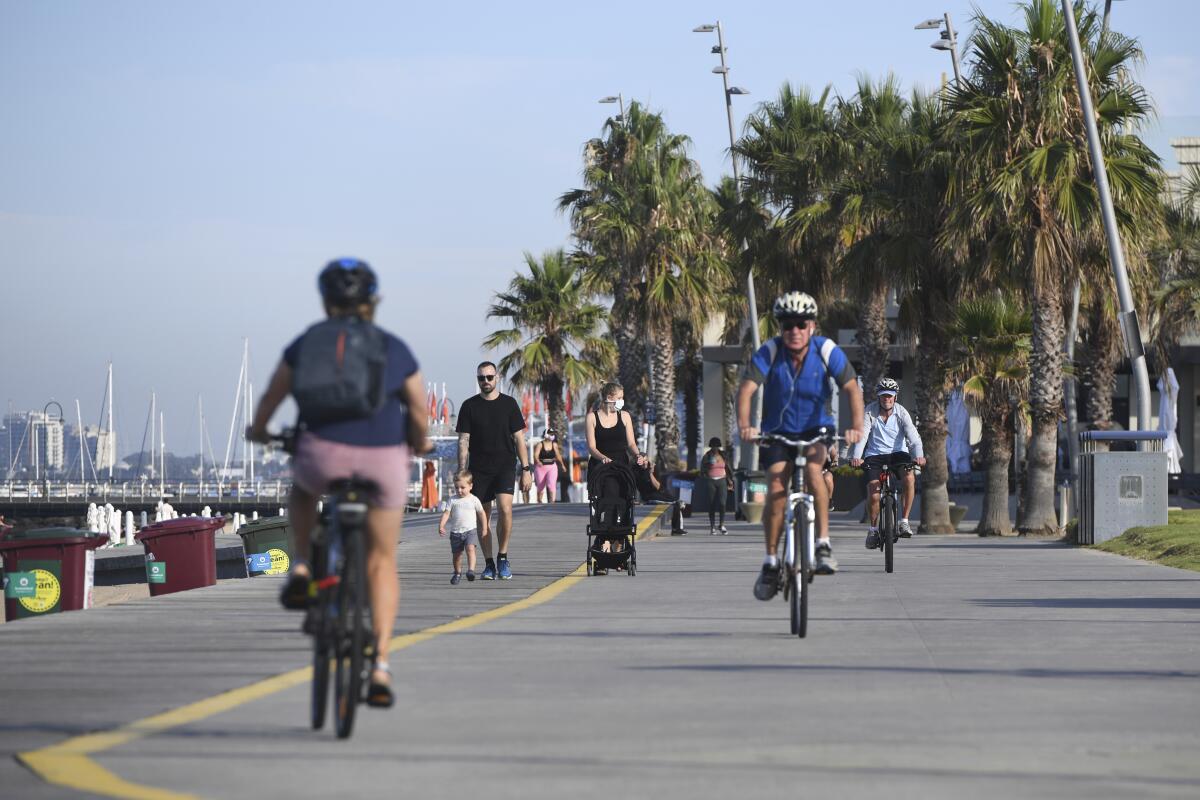 People walk and cycle at St. Kilda Beach in Melbourne, Australia