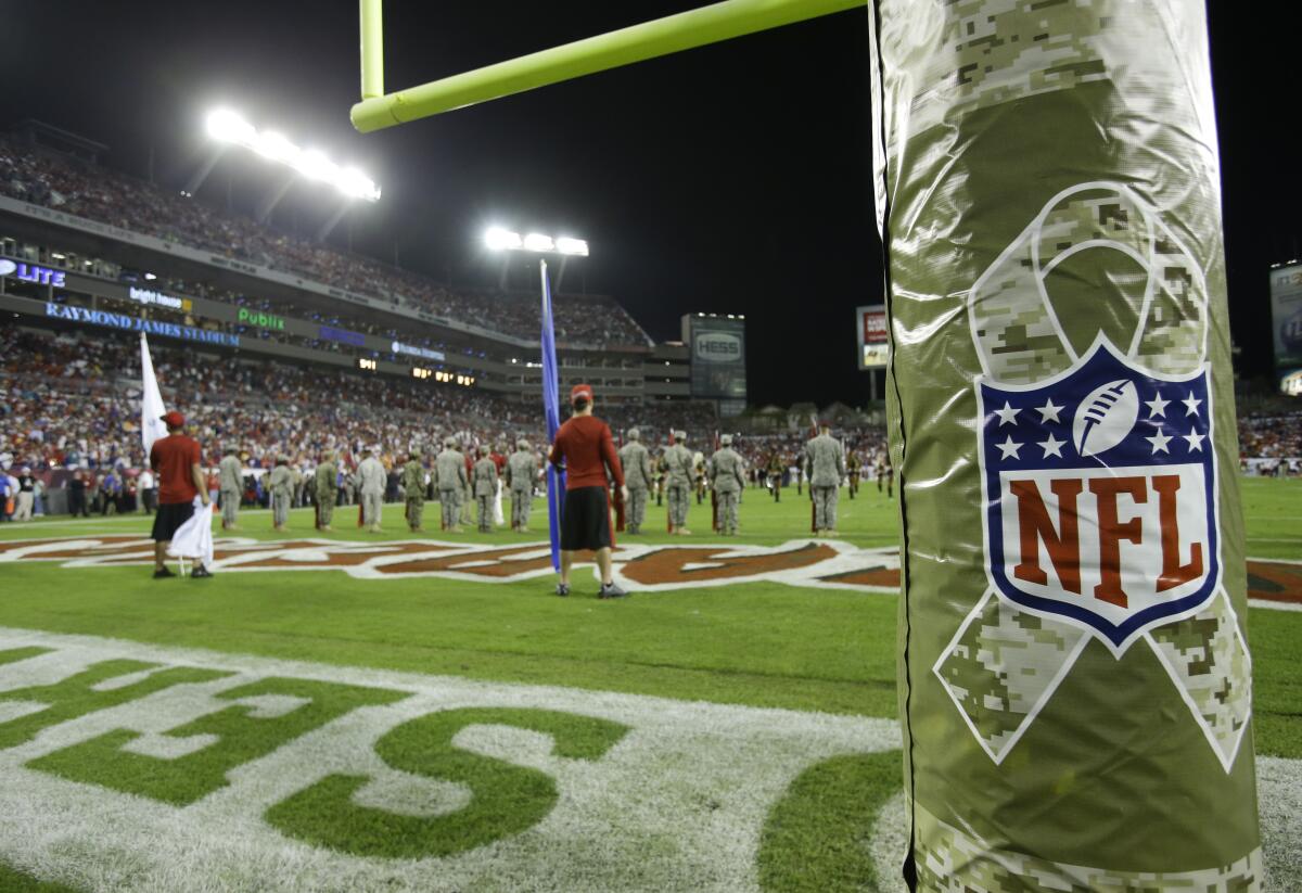 FILE - A goal posts is wrapped with the NFL logo in honor of Veterans Day during an NFL football game between the Tampa Bay Buccaneers and the Miami Dolphins in Tampa, Fla., on Nov. 11, 2013. Fox’s NFL pregame show is going international for the first time in 13 years for their annual Veterans Day show. This week’s “Fox NFL Sunday” will originate from Al Udeid Air Base in Qatar. (AP Photo/John Raoux, File)