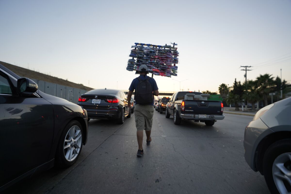 A street vendor works among stopped cars at the border.
