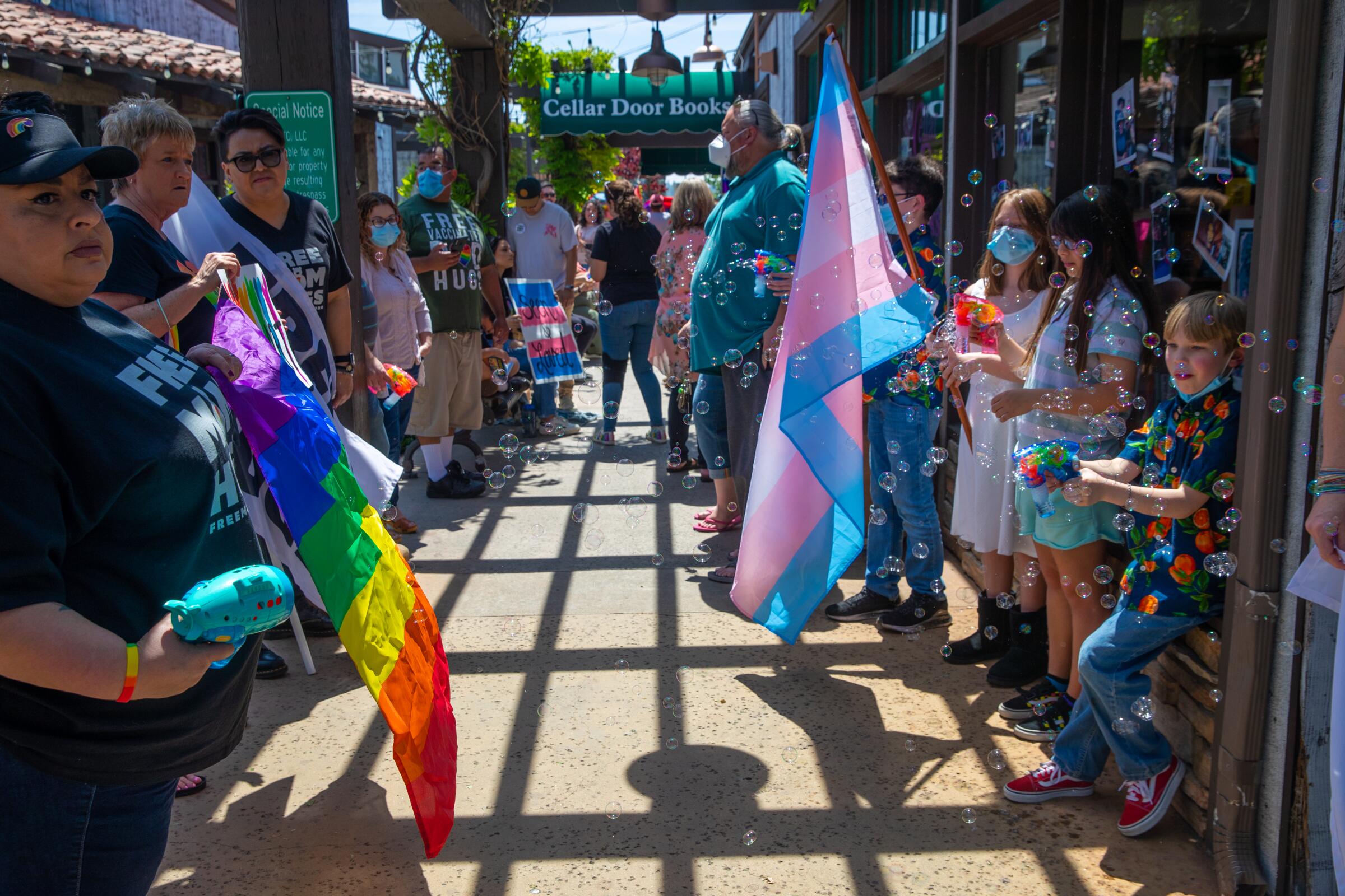 People stand outside a bookstore holding pride flags 