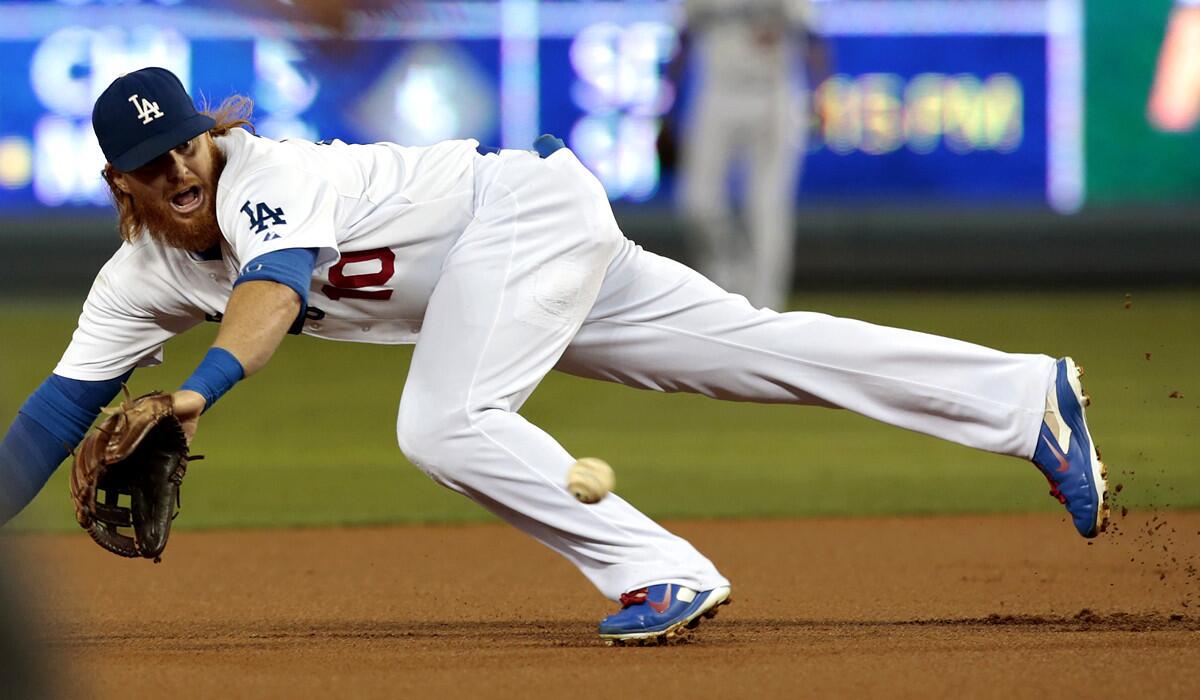 Dodgers shortstop Justin Turner makes a diving stop before making the throw to first base to put out Rockies hitter Rafael Ynoa in the first inning Friday night at Dodger Stadium.