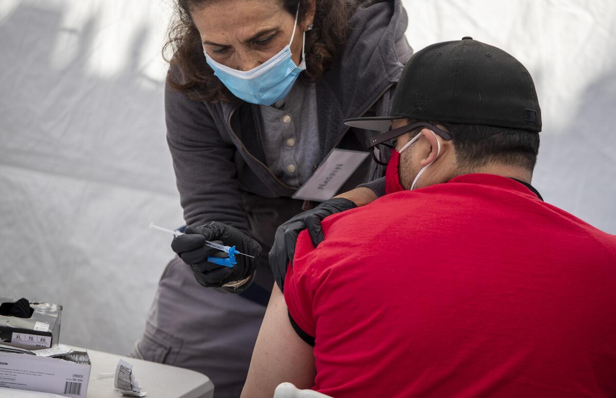 A pharmacist administers a COVID-19 vaccine.