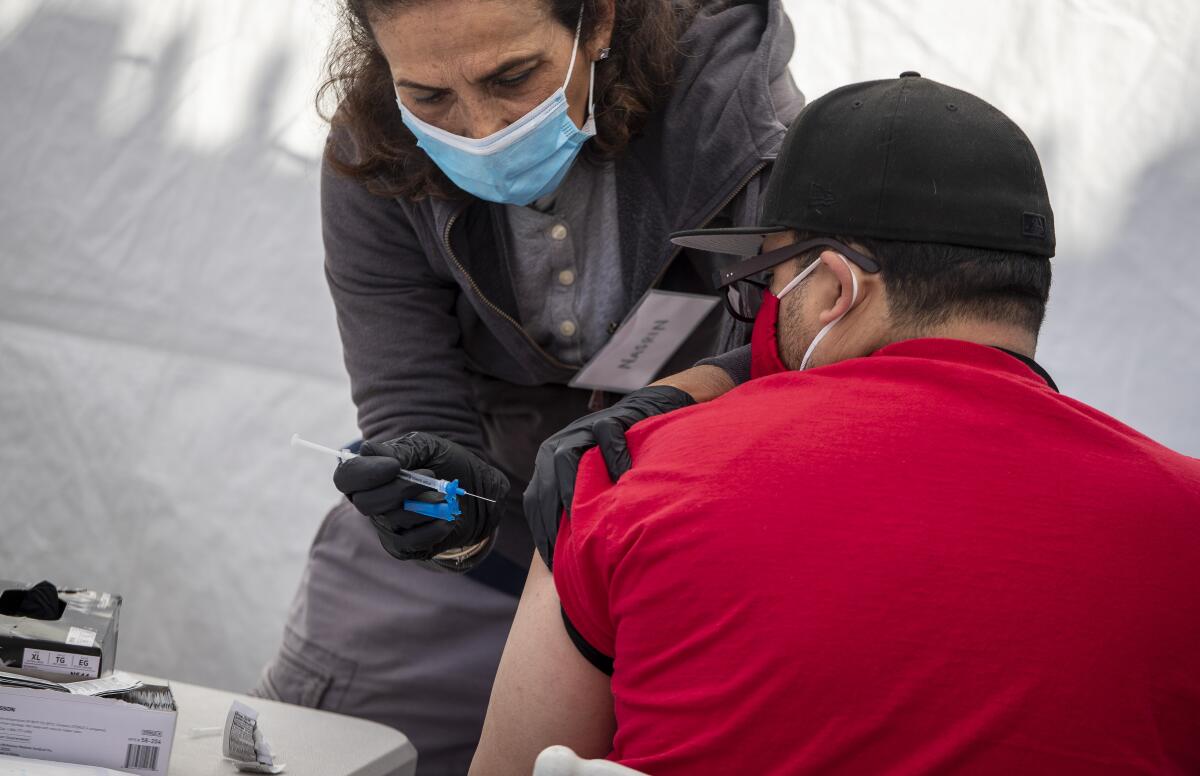 A pharmacist administers a COVID-19 vaccine.