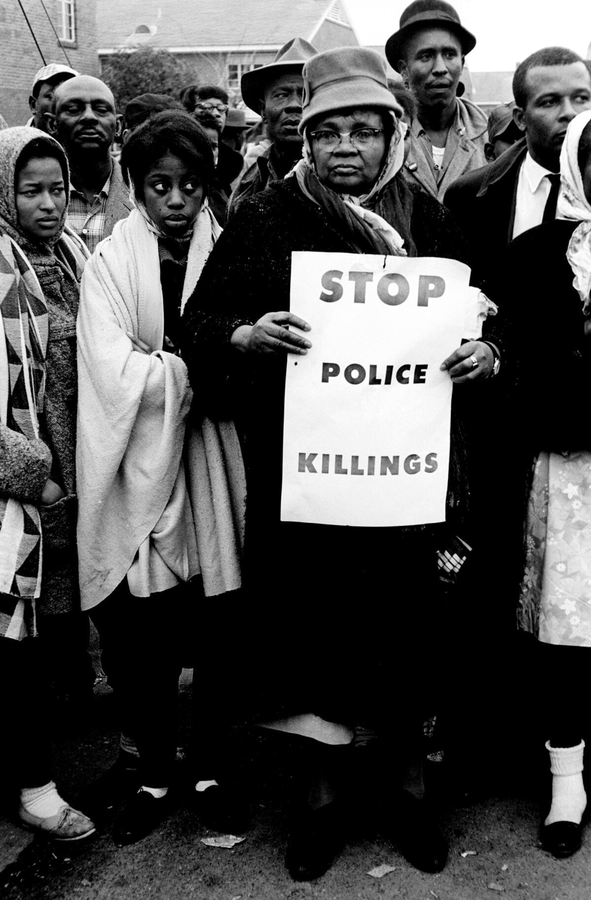 A woman holds a sign that says, "Stop police killings."