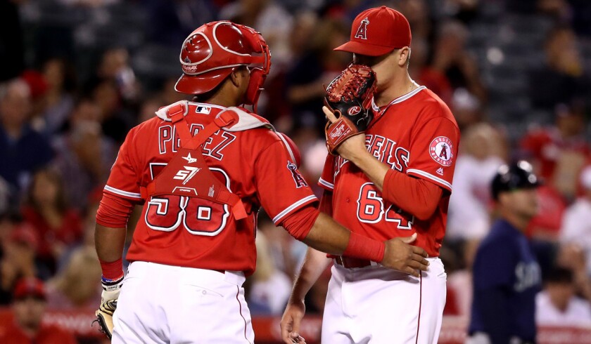 Angels catcher Carlos Perez (58) talks with pitcher Mike Morin (64) during the sixth inning against the Seattle Mariners on Tuesday.
