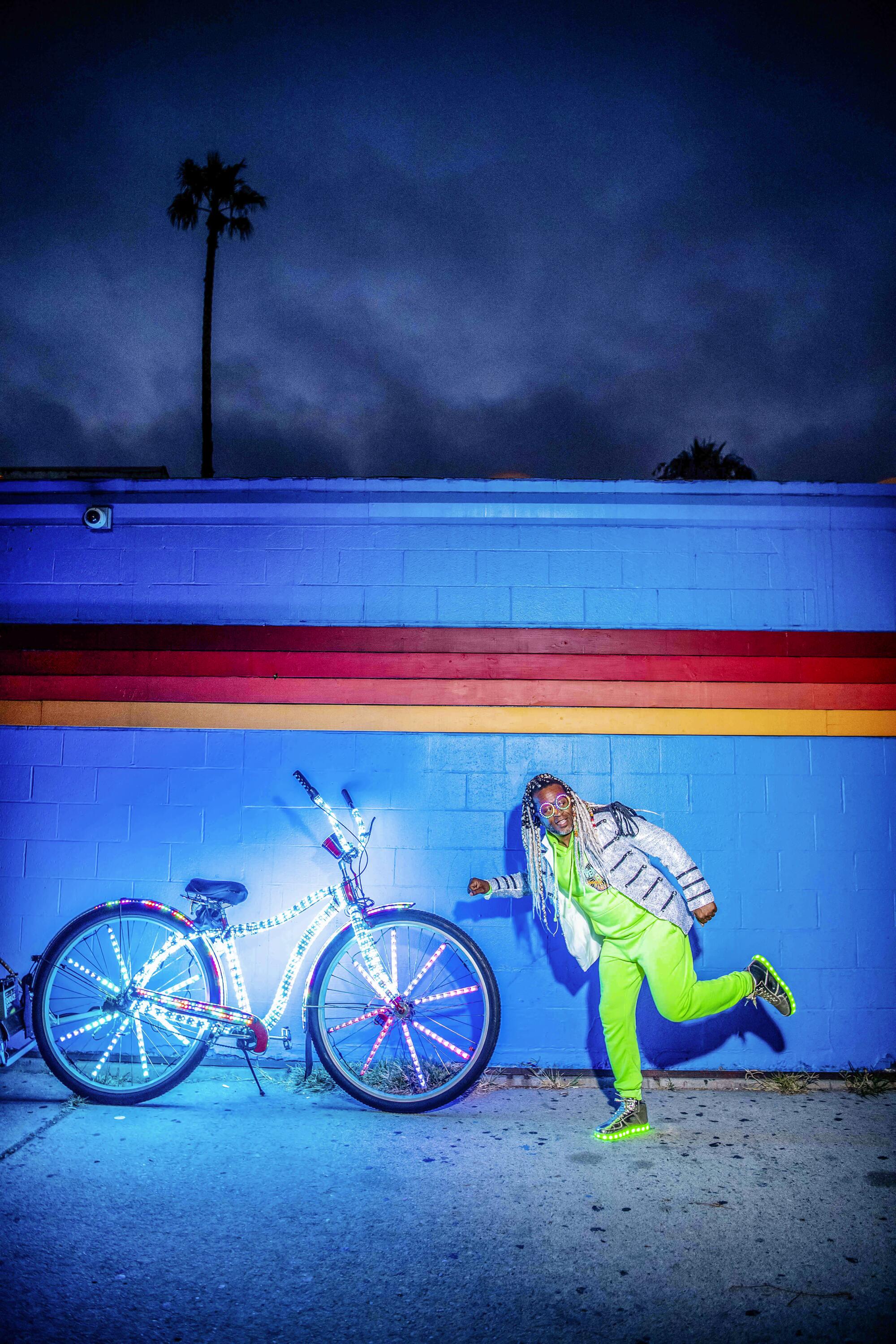 Marcus Gladney and his bike in front of a multicolored wall.