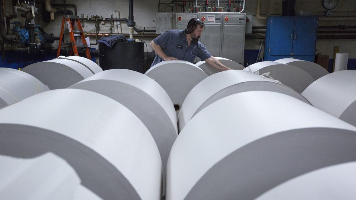 Jason Campbell adjusts rolls of newsprint before printing at the Columbian newspaper in Vancouver, Wash.