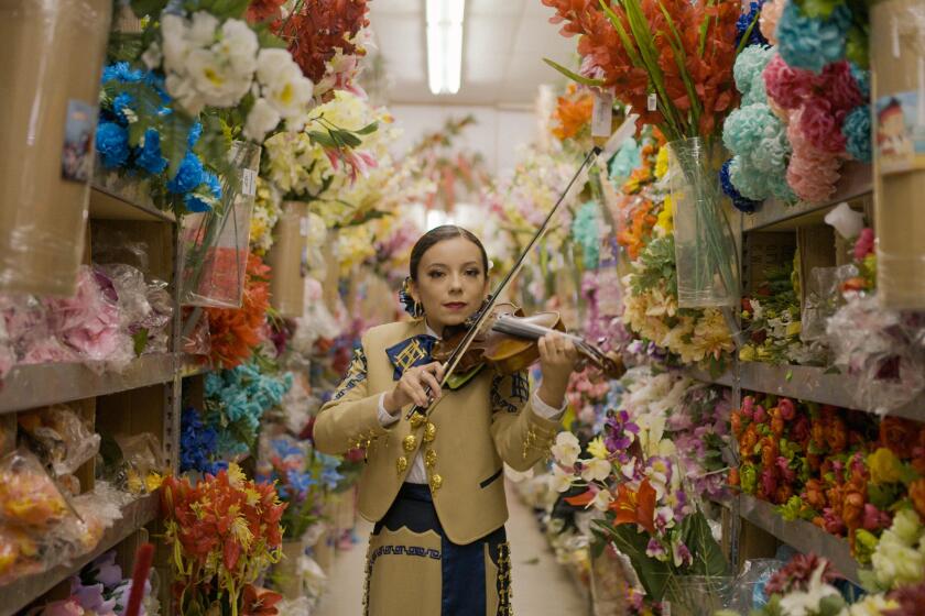 A woman mariachi plays a violin 