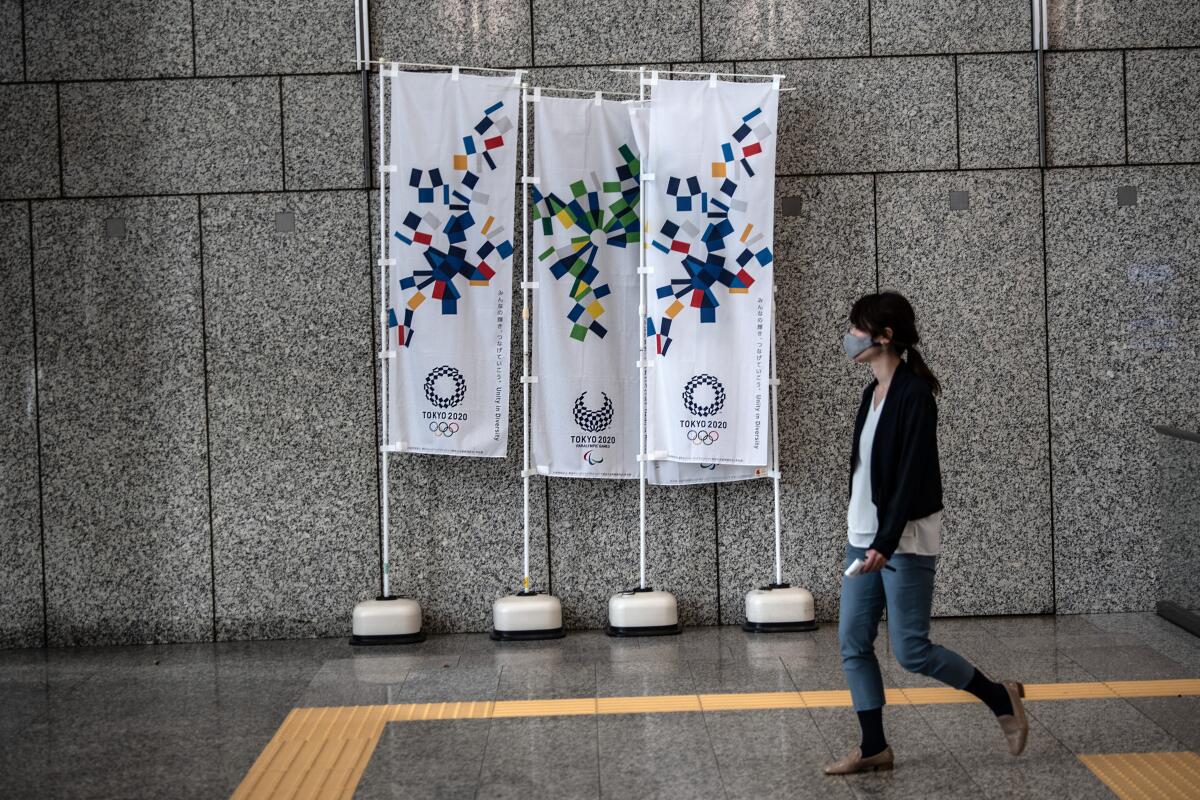 A woman walks past 2020 Olympics banners in Tokyo on March 19.
