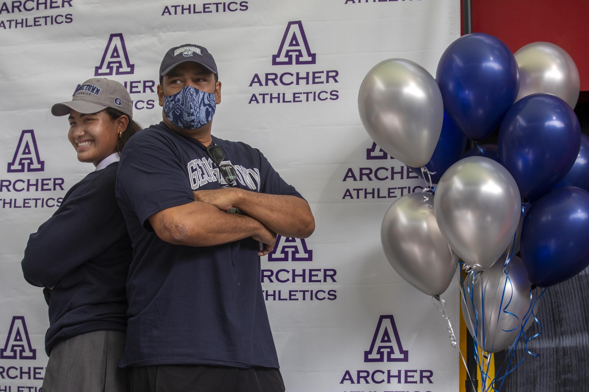 Vaughan Anoa'i stands back-to-back with her father, Reno Anoa'i, during a letter-of-intent signing ceremony 