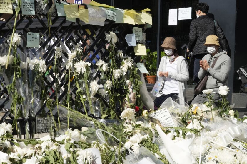 People pray for victims of a deadly accident during Saturday night's Halloween festivities, at a makeshift flower-laying area set up near the scene of the accident in Seoul, South Korea, Wednesday, Nov. 2, 2022. South Korean officials admitted responsibility and apologized on Tuesday for failures in preventing and responding to a Halloween crowd surge that killed more than 150 people and left citizens shocked and angry. (AP Photo/Ahn Young-joon)