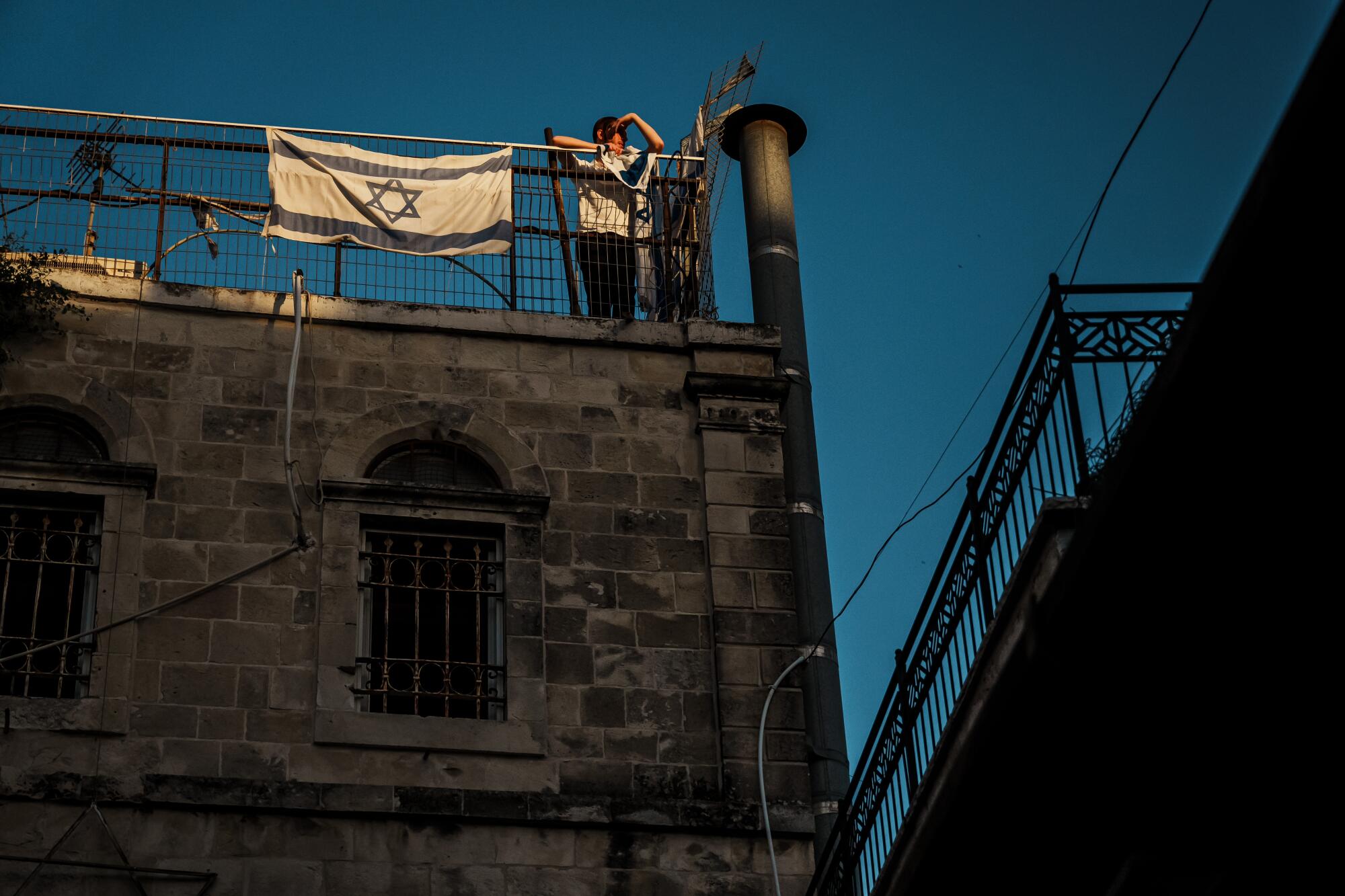 A man on a rooftop next to an Israel flag