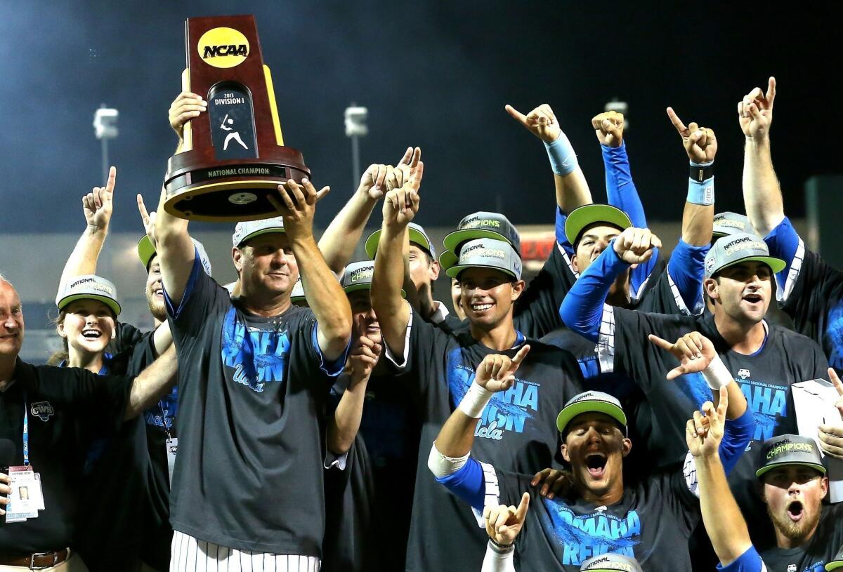 UCLA Coach John Savage holds up the championship trophy after the Bruins defeated the Mississippi State Bulldogs, 8-0, on Tuesday night to clinch the College World Series.