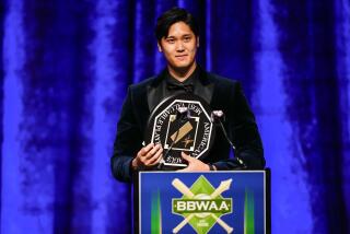 2023 American League MVP Shohei Ohtani wears a tuxedo and holds his award while speaking from a podium