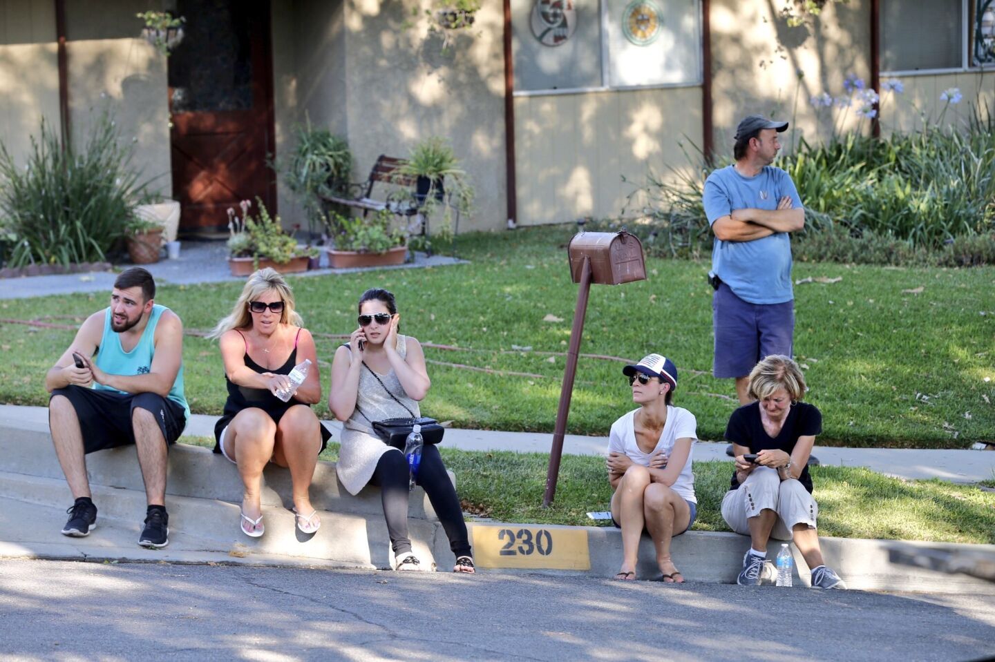 Duarte residents on Green Bank Avenue watch as firefighters battle a brush fire from the ground and the air.
