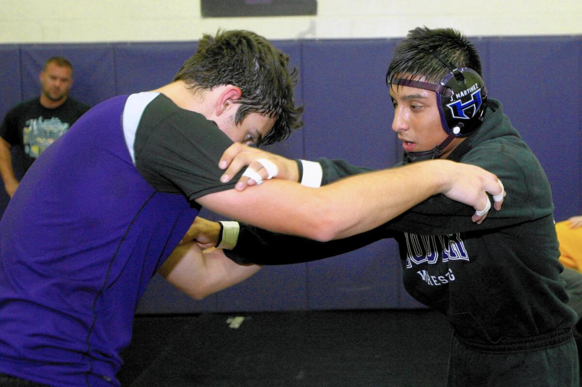 Hoover High School wrestlers Angelo Clarizio, left, and Jessie Martinez, right, learn take-down moves during practice at the school's gym in Glendale on Friday, Nov. 20, 2015.