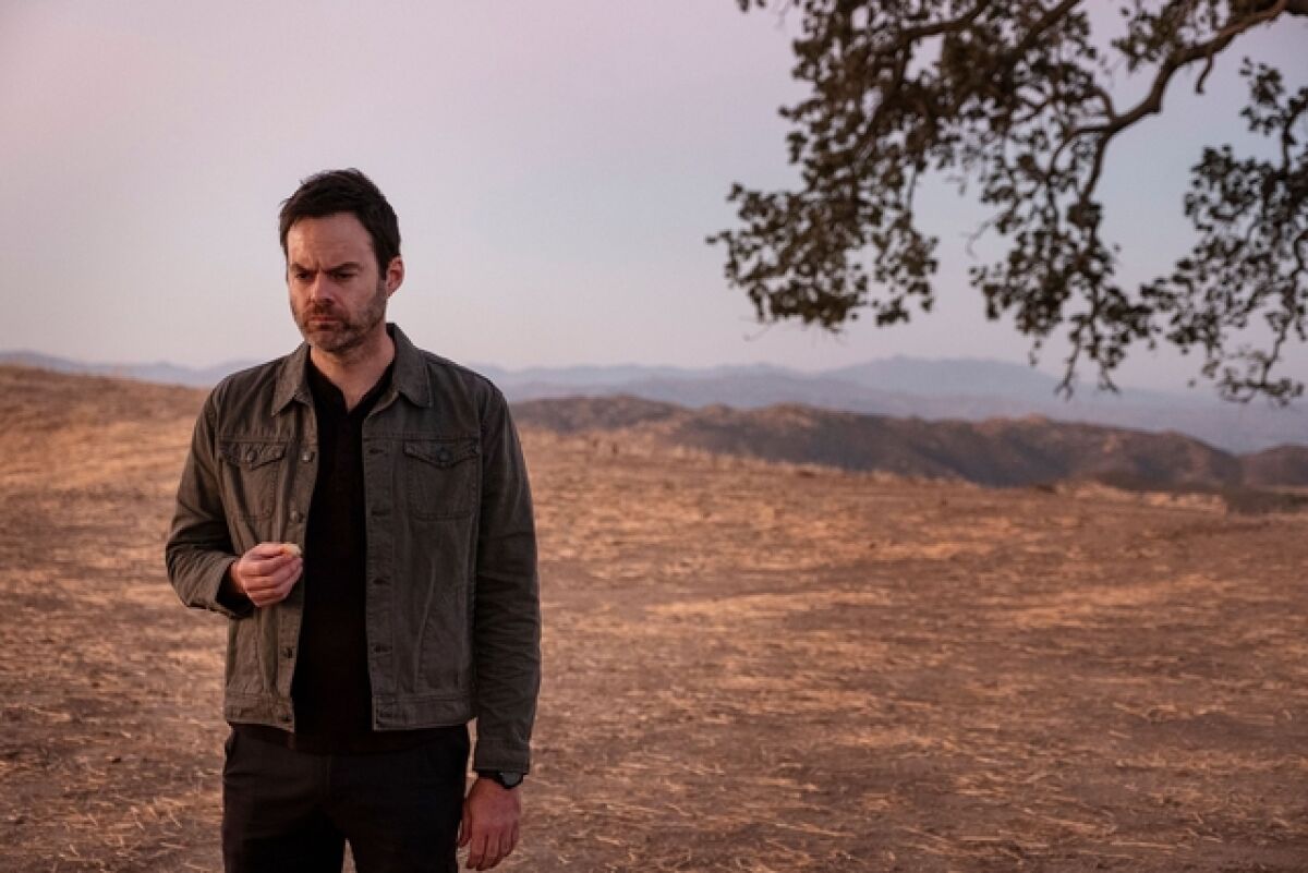 Bill Hader stands by a lone tree with a barren hillside behind him
