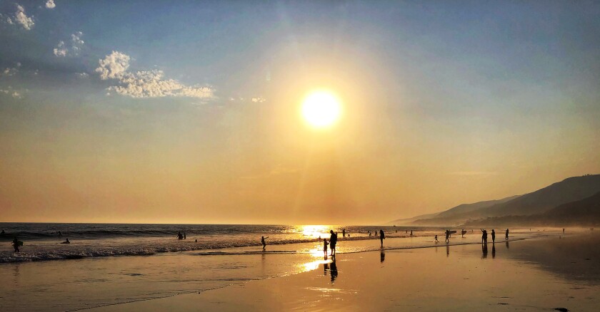 Beachgoers sample the waves at L.A. County's Zuma Beach shortly before sunset on Saturday.