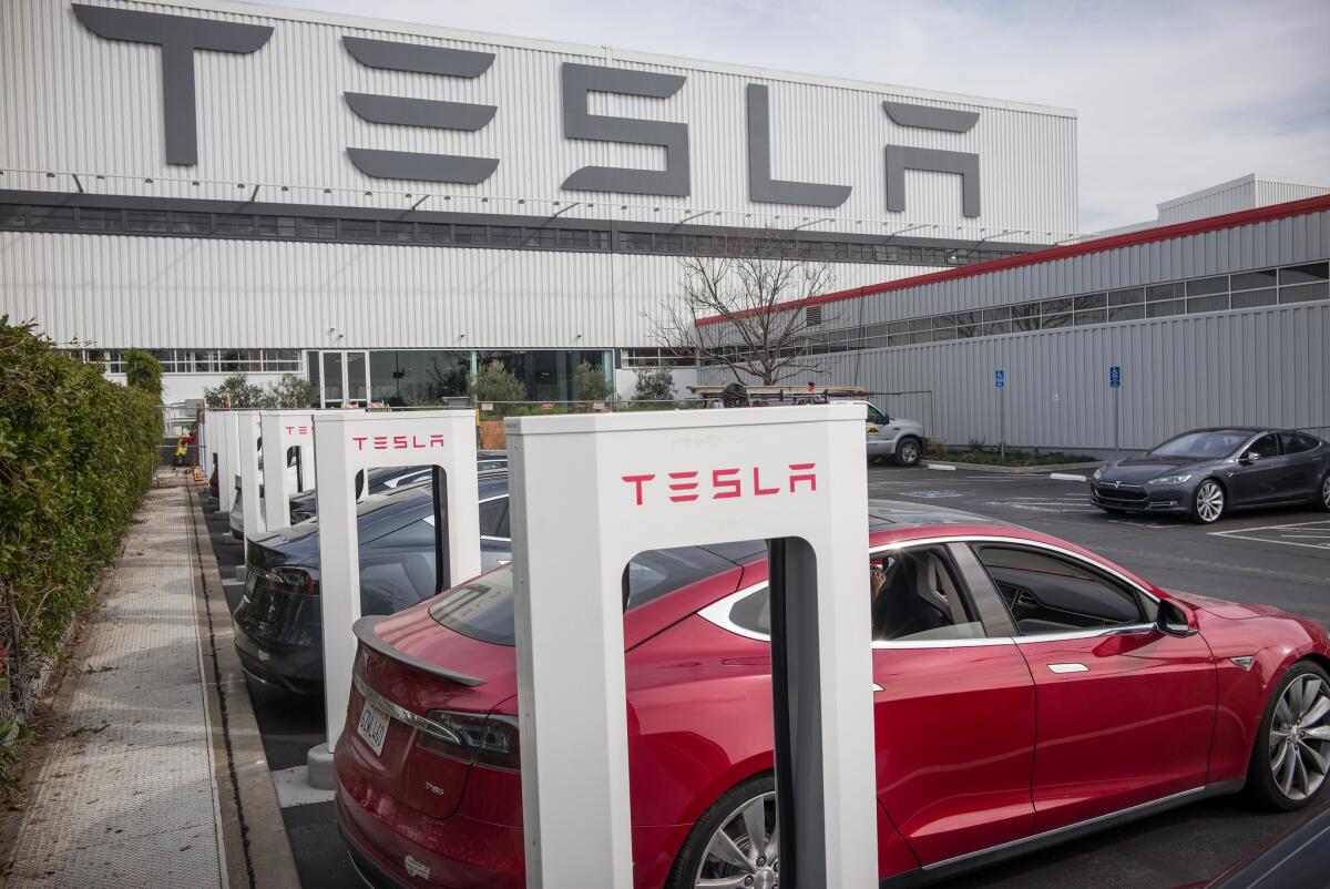 Cars charge at stations outside of Tesla's factory in Fremont.