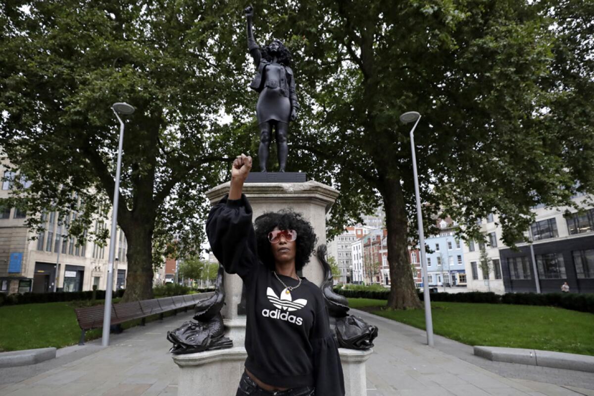 Activist Jen Reid stands, fist raised, before the statue made in her likeness by artist Marc Quinn.