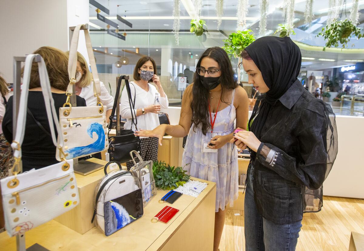 Ayah Mohamed, 17, left, shows off handbags to Hilal Balik, at an event at Hammitt - South Coast Plaza on Thursday. 