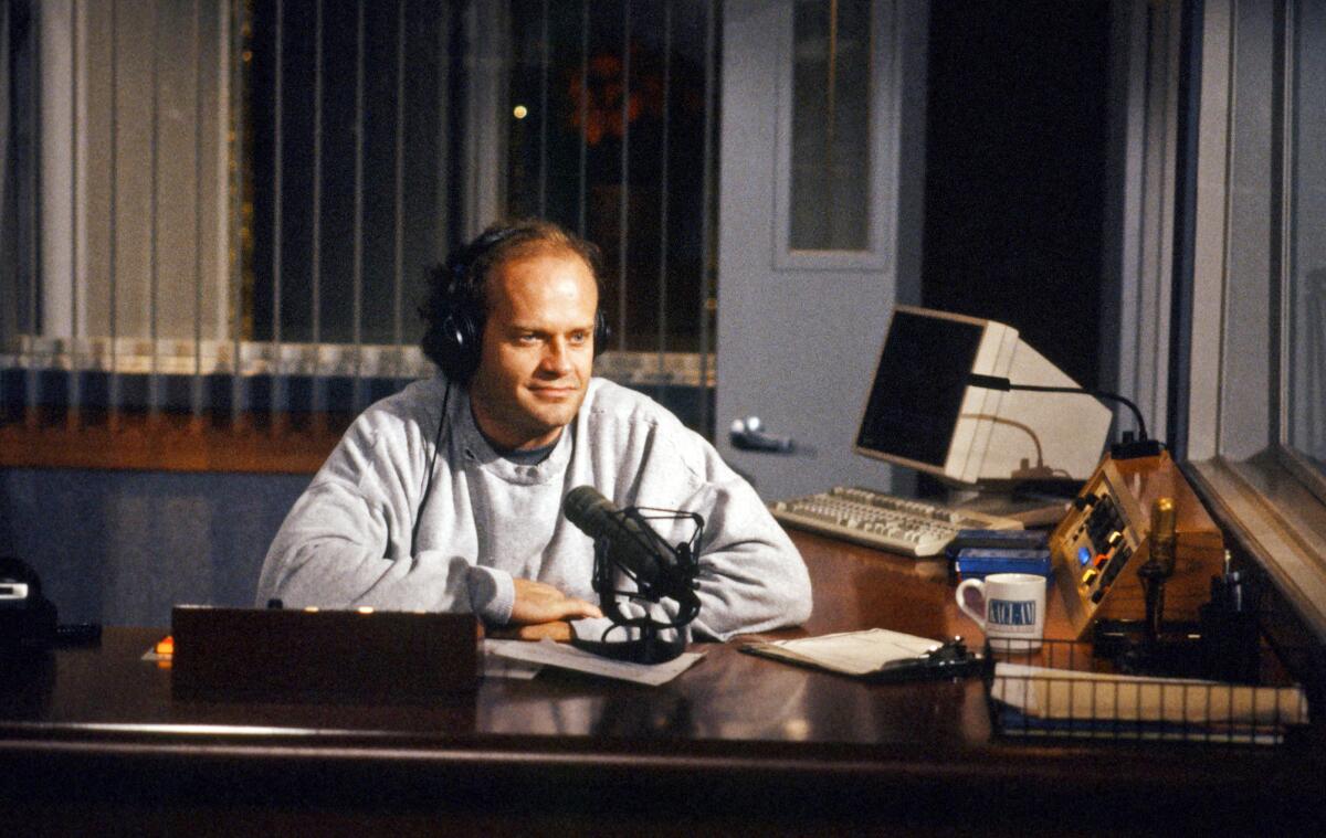 Kelsey Grammer, as Frasier Crane, speaks into a microphone on his office desk in "Frasier."