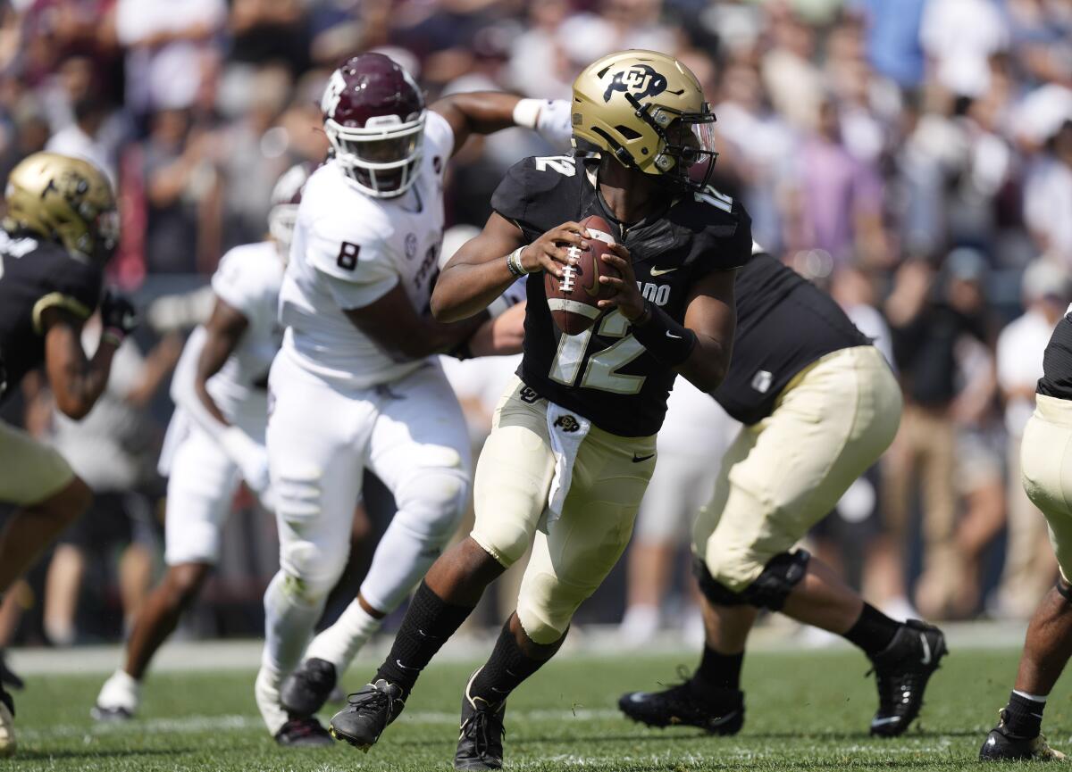 Colorado quarterback Brendon Lewis, front, rolls out to pass as Texas A&M defensive lineman DeMarvin Leal pursues in the first half of an NCAA college football game, Saturday, Sept. 11, 2021, in Denver. (AP Photo/David Zalubowski)
