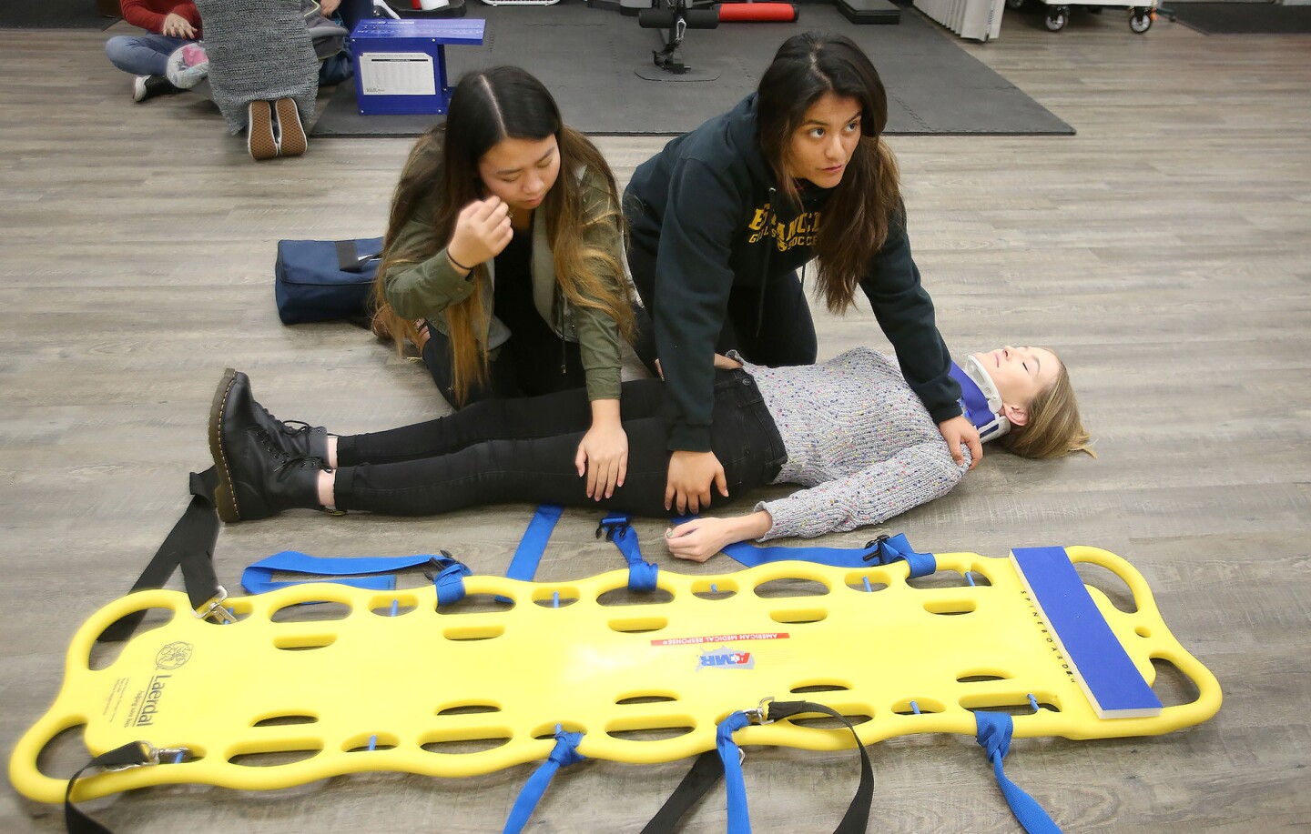 Two students prepare classmate Kenna Cowie to be placed on a backboard as they practice stabilizing a patient with head or neck injuries during an Estancia Medical Academy class Thursday.