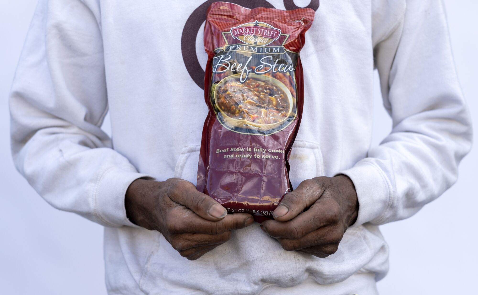 A man holds a bag of beef stew.