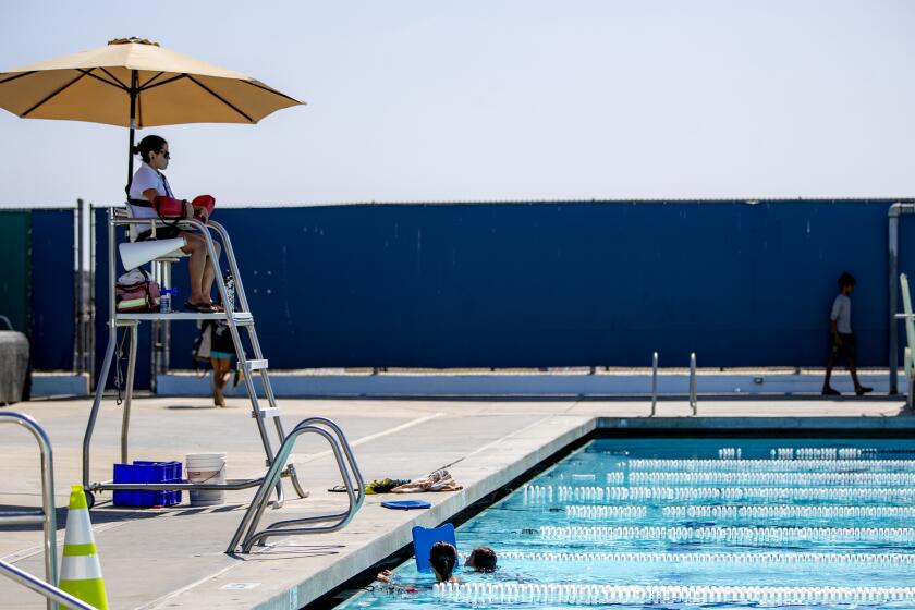 CARLSBAD, CA- JUNE 30, 2022: Senior lifeguard Ravelle Morales, 28, keeps an eye on swimmers at Monroe Street Pool on June 30, 2022 in Carlsbad, California. Morales has been lifeguarding for 9 years. There is a lifeguard shortage in California. Right now, there is a new bill AB 1672 that would allow ocean lifeguards to work at public pools amidst this shortage.(Gina Ferazzi / Los Angeles Times)