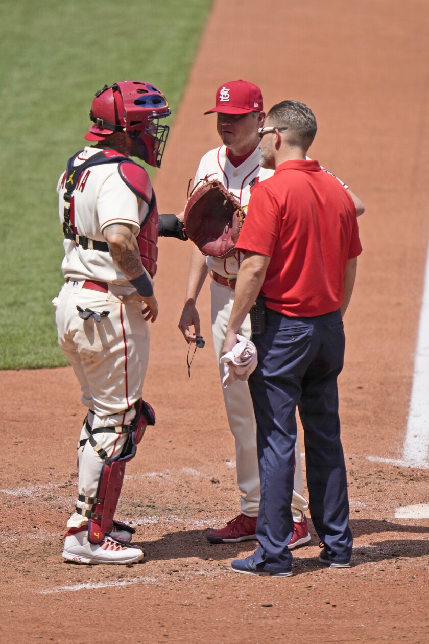 St. Louis Cardinals catcher Yadier Molina, left, talks with manager Mike Shildt and trainer Adam Olsen after being injured during the fourth inning of a baseball game against the Cincinnati Reds Saturday, June 5, 2021, in St. Louis. (AP Photo/Jeff Roberson)