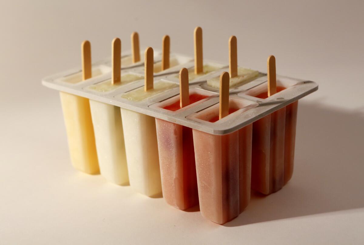 A plastic container holds popsicles with sticks.