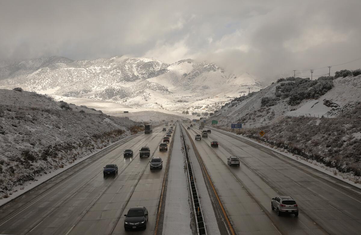 Cars are shown on a freeway with snowy mountains in the background.