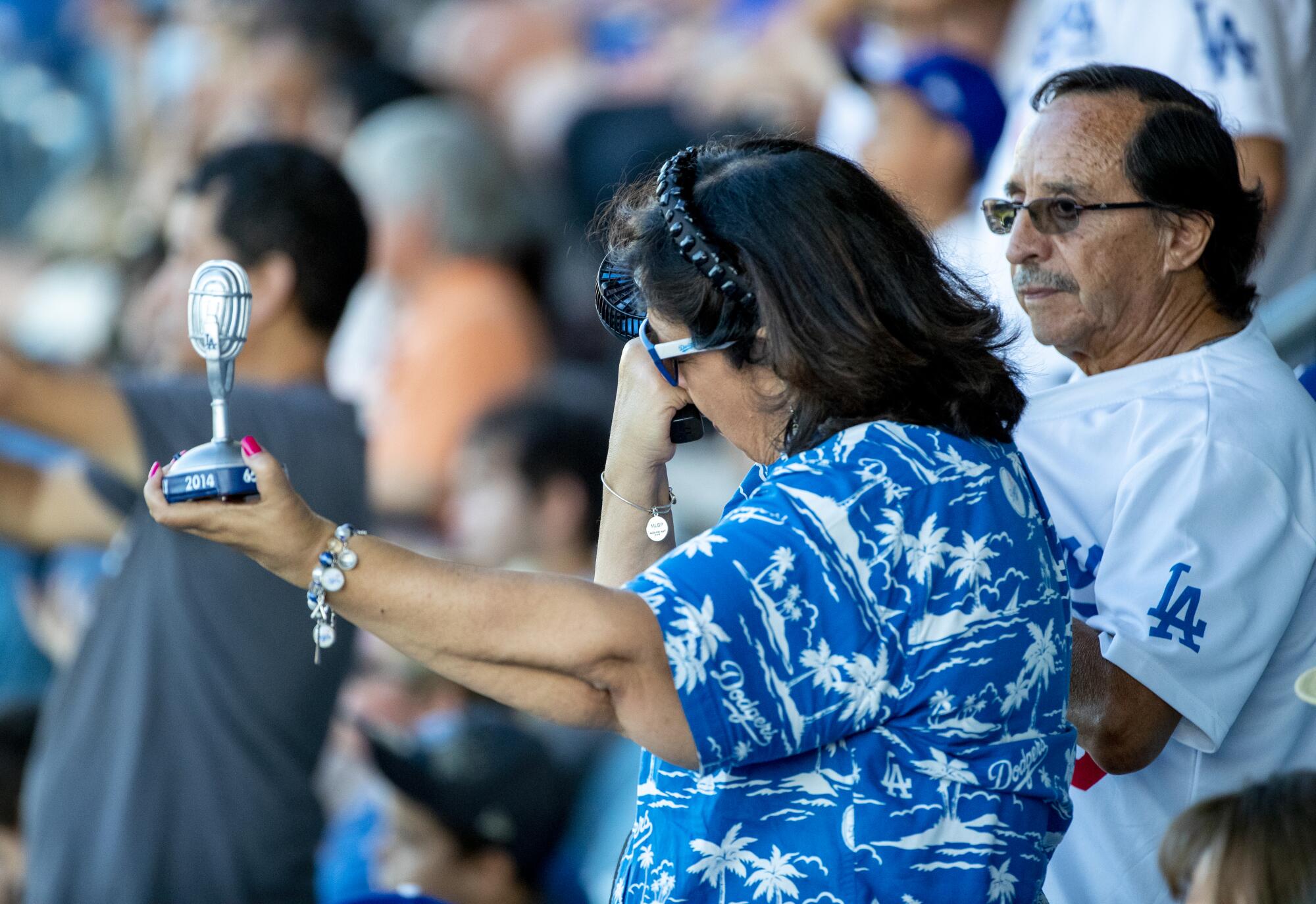 Dodgers fan Angie Varella wipes tears while holding a replica microphone.