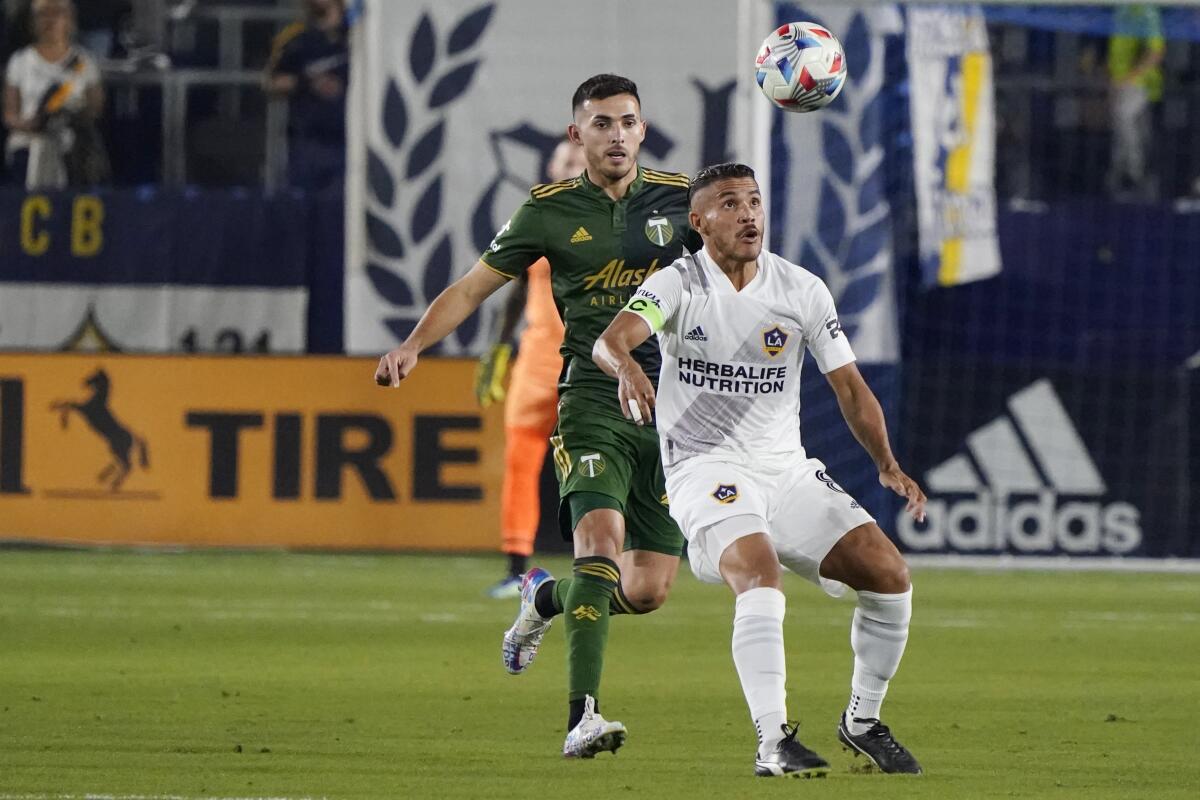 Galaxy midfielder Jonathan dos Santos controls the ball in front of Timbers midfielder Cristhian Paredes
