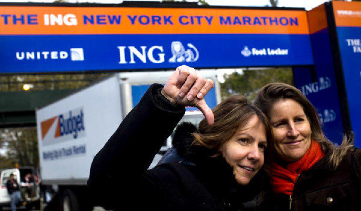 Celine Bally, of French Martinique, gives a thumbs-down in front of the Central Park finish line of the canceled New York Marathon. Some people who planned to run in that race have switched to the Malibu marathon, which will be held Sunday.