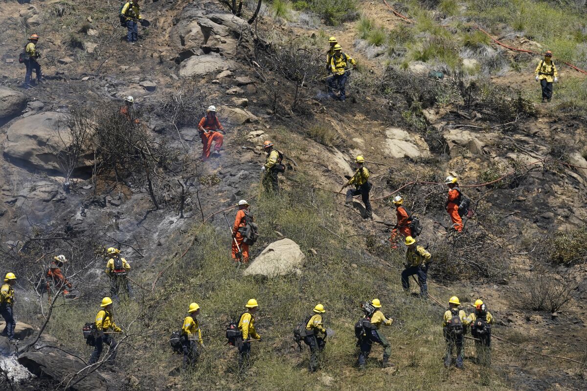 Crews battle a brush fire along the 118 freeway Wednesday, April 6, 2022, in Chatsworth, Calif. California's weather roller coaster is headed up, with forecasts for widespread summerlike heat. (AP Photo/Marcio Jose Sanchez)